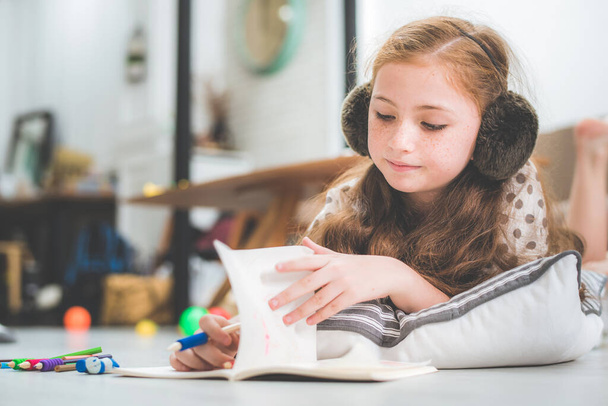 μικρό χαριτωμένο κορίτσι σπουδάζει και να διαβάσετε το βιβλίο στο σπίτι, την έννοια της εκπαίδευσης  - Φωτογραφία, εικόνα