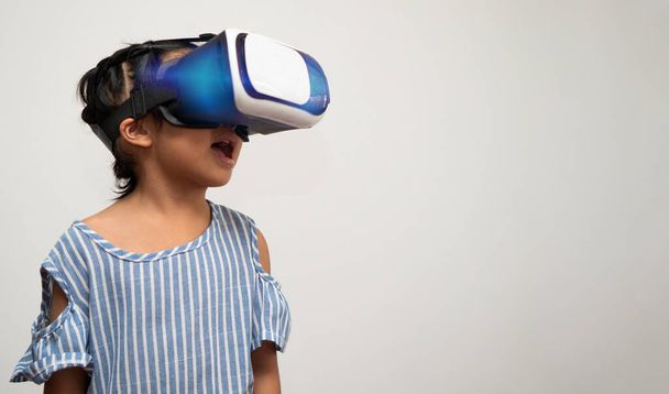 Little Asian girl child with virtual reality headset is exciting for new experiencing. Concept of 3D gadget technology and virtual world gadgets game and online education in the future - Photo, Image