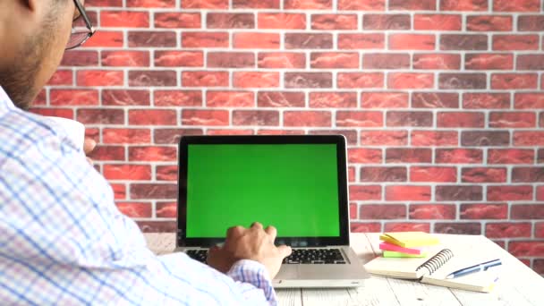 zadní pohled mladého muže pomocí notebooku s prázdnou obrazovkou na kancelářském stole. - Záběry, video