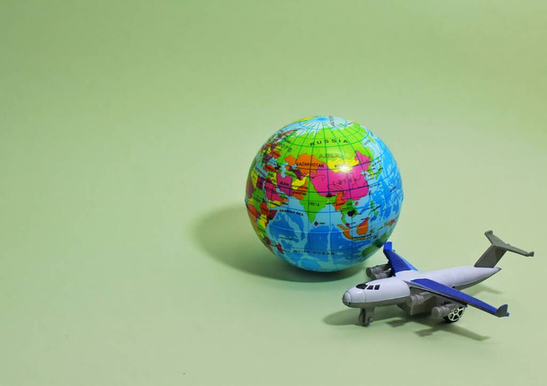 コピースペースと緑の背景におもちゃの飛行機と地球の地球。選択的焦点. - 写真・画像