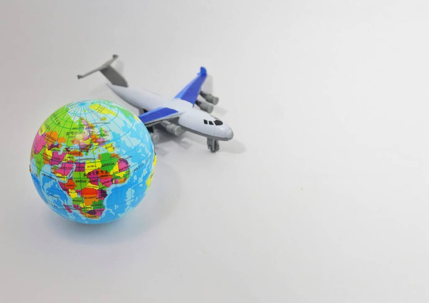 Toy plane and earth globe on white background with copy space. Selective focus. - 写真・画像