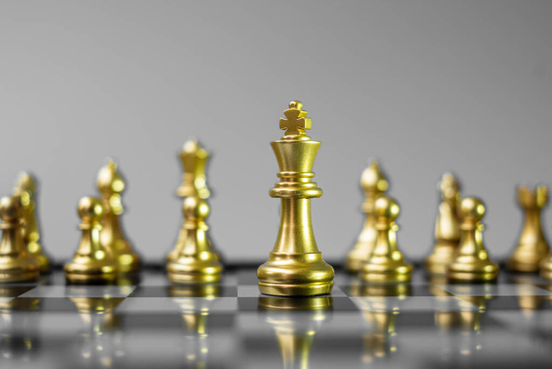 Χρυσή σκακιστική ομάδα (Βασιλιάς, Βασίλισσα, Επίσκοπος, Ιππότης, Πύργος και Πιόνι) στη σκακιέρα εναντίον αντιπάλου κατά τη διάρκεια της μάχης. Στρατηγική, επιτυχία, διαχείριση, επιχειρηματικό σχεδιασμό, τακτική, πολιτική και ηγετική έννοια - Φωτογραφία, εικόνα