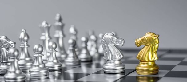 Zlato a stříbro Šachy Knight (kůň) figurka na šachovnici proti soupeři nebo nepříteli. Strategie, Konflikt, management, obchodní plánování, taktika, politika, komunikace a vedoucí koncepce - Fotografie, Obrázek