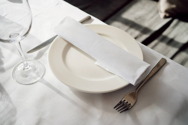сервируя стол. белая пустая тарелка с салфеткой, ножом и вилкой. - Фото, изображение