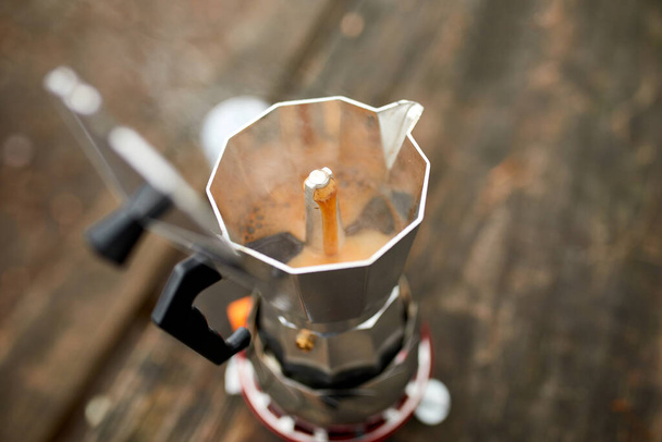 Prozess der Herstellung von Camping-Kaffee im Freien mit Metall-Geysir-Kaffeemaschine auf einem Gasbrenner, gießt durch die Löcher, Schritt für Schritt. Reiseaktivitäten für Entspannung, Buschboot, Abenteuer, Reisen, Tourismus und Campingkonzept - Foto, Bild