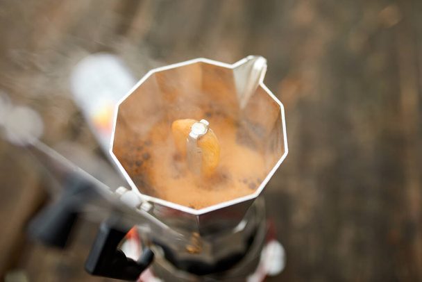 Metal gayzer kahve makinesiyle dışarıda kahve yapma süreci gaz ocağında, deliklerden adım adım akıyor. Rahatlama, çalılık, macera, seyahat, turizm ve kamp konsepti için seyahat etkinliği - Fotoğraf, Görsel