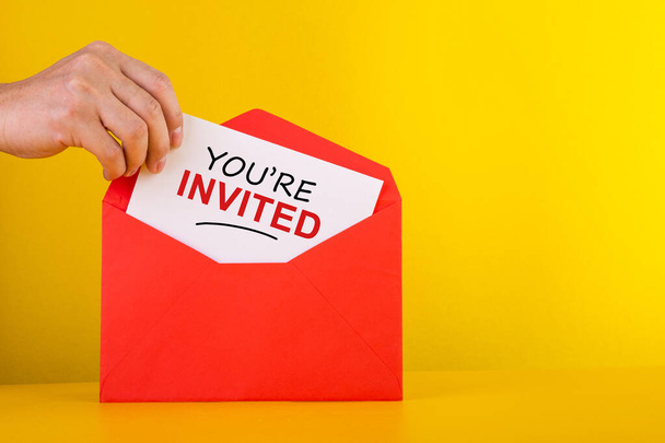 Είστε προσκεκλημένοι Concepts - χέρι κρατώντας μια κάρτα με κόκκινο φάκελο. - Φωτογραφία, εικόνα