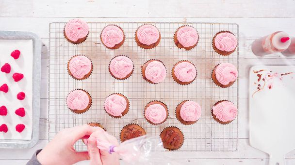 Flat lay. Frosting chocolate cupcakes with raspberry cream cheese buttercream. - Photo, Image