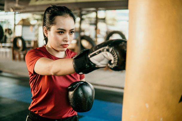 young woman boxer doing exercise hitting punching bag - Photo, image