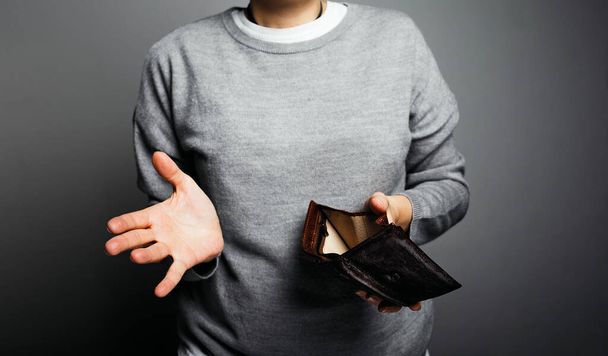 Woman in gray sweater looking into empty wallet, post-quarantine crisis concept - Fotó, kép