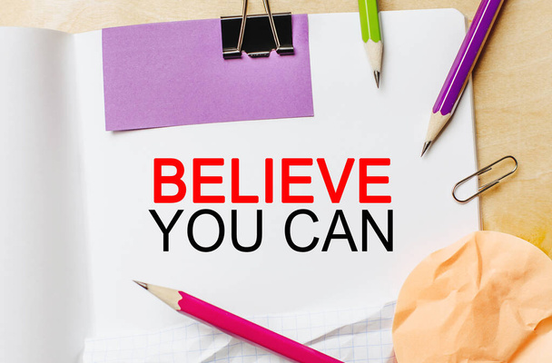 Text Believe you can on a white notepad with pencils on a wooden background. Business concept - 写真・画像