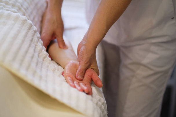 Handgelenkmassage. Massagetherapeutin übt Druck auf einen sensiblen Punkt auf eine Frauenhand aus. Physiotherapeutin massiert ihre Patienten in Arztpraxis - Foto, Bild