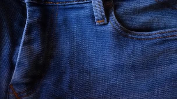 Niebieskie jeansy zamykają materiał 4K. Niebieskie dżinsy dżinsy w zbliżeniu z przesuwnymi ruchami kamery. - Materiał filmowy, wideo