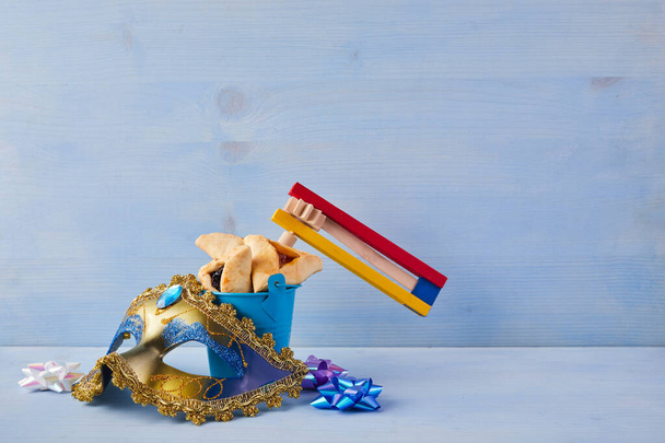 Purim celebration concept with hamantashen cookies, Purim mask and toy noisemaker on blue background - Photo, Image