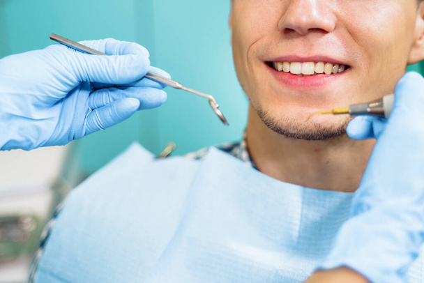 Tıbbi aletlerle dişçinin ellerini yakın plan çek. Büyük ayrıntı, dişçinin aynası, kıvrılma ve sonda. Diş sorunlarının çözümü kendinden emin, profesyonel jestlerle etkili. - Fotoğraf, Görsel