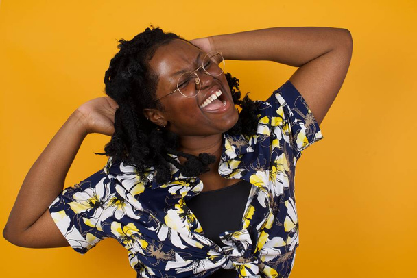 Fiducia e concetto civettuolo. Ritratto di affascinante giovane donna afroamericana che indossa abiti casual sorridendo ampiamente con espressione sicura di sé mentre si tiene per mano sopra la testa. - Foto, immagini