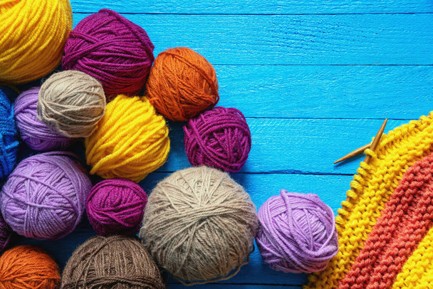 Hobbies and knitting concept.  Colorful balls of wool and  knitted cloth with knitting needles on  blue rustic table. Copy space - Photo, Image
