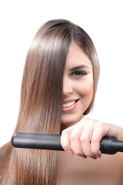 Woman doing hairstyle with hair straightener isolated on white - Valokuva, kuva