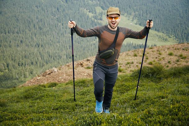 gelukkige wandelaar met professonal apparatuur in de bergen, man schreeuwen en klimmen de berg - Foto, afbeelding