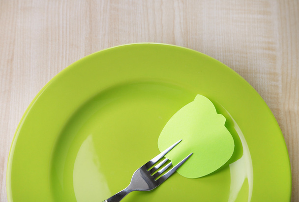 Empty note paper attached to fork, on plate, on color wooden background  - Foto, afbeelding