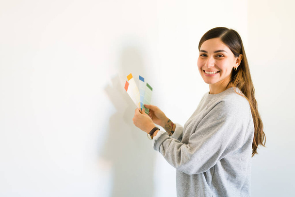 Egy gyönyörű független nő portréja, aki eldönti, milyen színűre festi a falakat. Fiatal nő újradekorálja új otthonát - Fotó, kép
