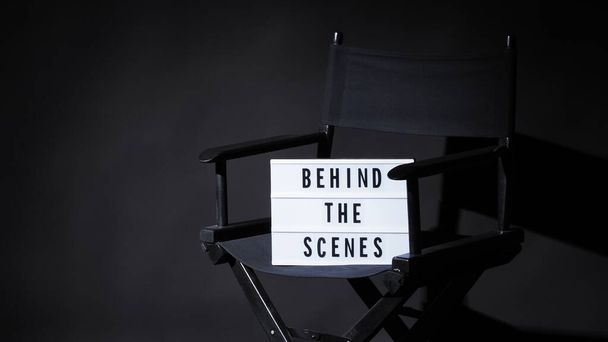 A színfalak mögött felirat a Lightbox-on vagy a Cinema Light boxon. Filmvászon és rendezői szék. Háttér fekete szín. fényképezőgép forgatás a videó gyártási stúdióban. - Fotó, kép
