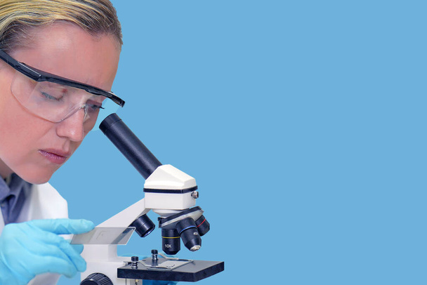 大学の研究室で顕微鏡を通して見ている女性生化学者の学生.医療技術・医薬品研究開発科学の概念. - 写真・画像