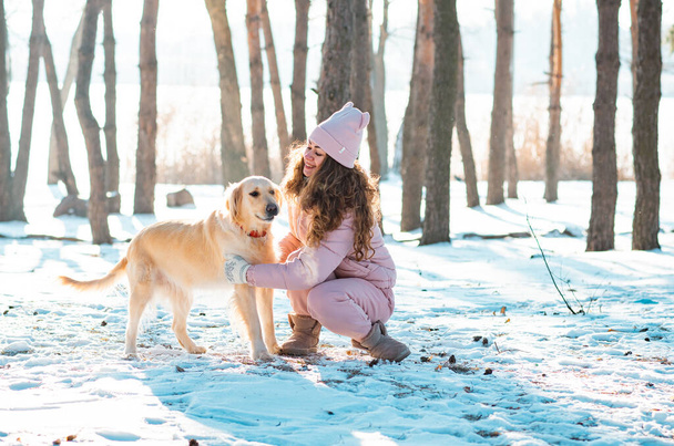 Mladá dívka hraje zlatý retrívr pes ve sněhu - Fotografie, Obrázek