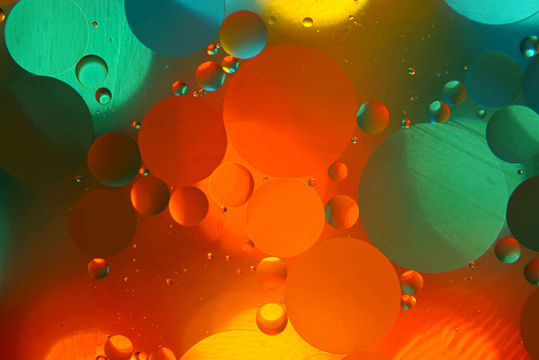 Mooie kleur abstracte achtergrond op basis van rode, groene en gele cirkels, macro abstractie. Mengen van water en olie - Foto, afbeelding