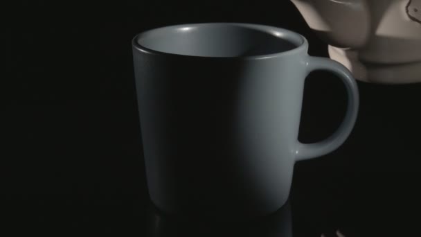 A teát kerámia pohárba öntik. Közelkép fekete háttérrel. - Felvétel, videó