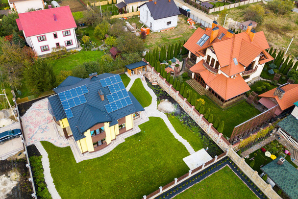 Luftaufnahme eines ländlichen Privathauses mit Photovoltaik-Sonnenkollektoren zur Produktion sauberen Stroms auf dem Dach. Autonomes Wohnkonzept. - Foto, Bild
