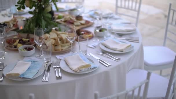 Una mesa de servicio decorada con un ramo de flores y elegantes sillas blancas en el banquete de bodas - Metraje, vídeo