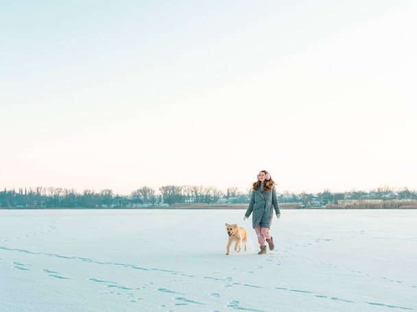 Portret Młoda kobieta w parku zimowym spacerująca z psem golden retriever. Przyjaźń, zwierzak i człowiek. - Zdjęcie, obraz