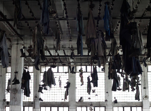Umkleideraum einer alten Industriefabrik: Arbeitskleidung hängt von der Decke - Foto, Bild
