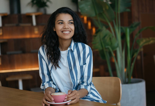 Mladá krásná žena drží šálek kávy sedí v kavárně. Koncept přestávky na kávu  - Fotografie, Obrázek