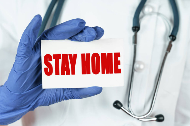 Medicine concept. The doctor holds a business card that says - STAY HOME - Foto, immagini