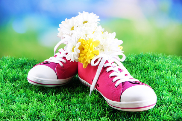 Beautiful gumshoes with flowers inside on green grass, on bright background - Fotó, kép
