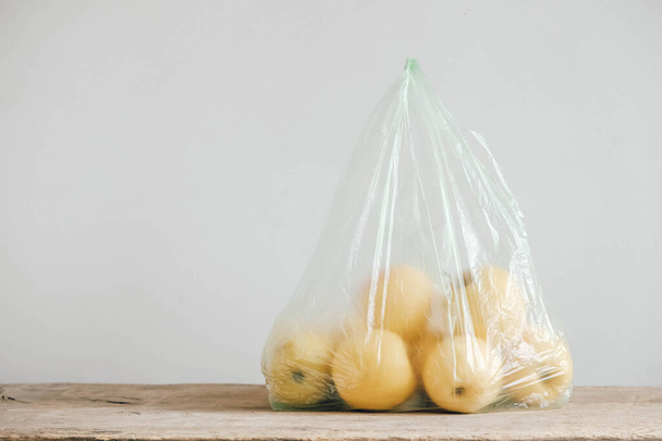 Tahta bir masada plastik bir torbada sarı elmalar. Kopyala, metin için boşluk. - Fotoğraf, Görsel