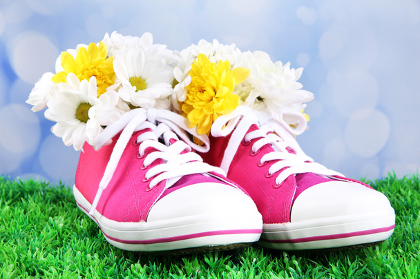 Beautiful gumshoes with flowers inside on green grass, on bright background - Foto, imagen