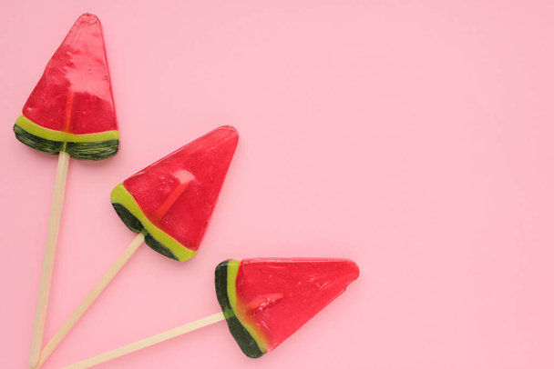 Watermelon popsicle on pink colored backdrop. Bright summer background. Lollipop in piece of watermelon shape. Candy on a stick. Top view, copy space - Photo, Image