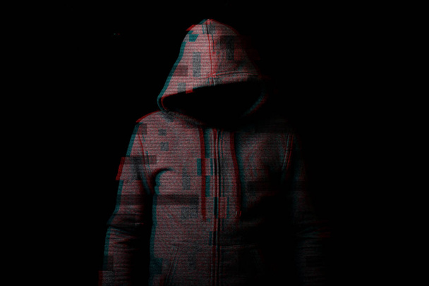 Un uomo senza una faccia in un cappuccio su uno sfondo scuro. Aggiunto effetto glitch. - Foto, immagini