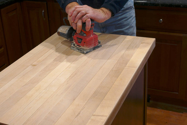 Using an electric sander to refinish a counter top - Photo, Image