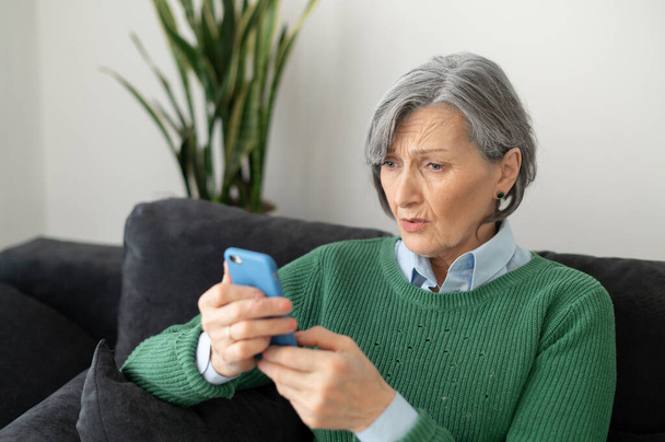 Surprised senior woman holding a mobile phone - Photo, Image