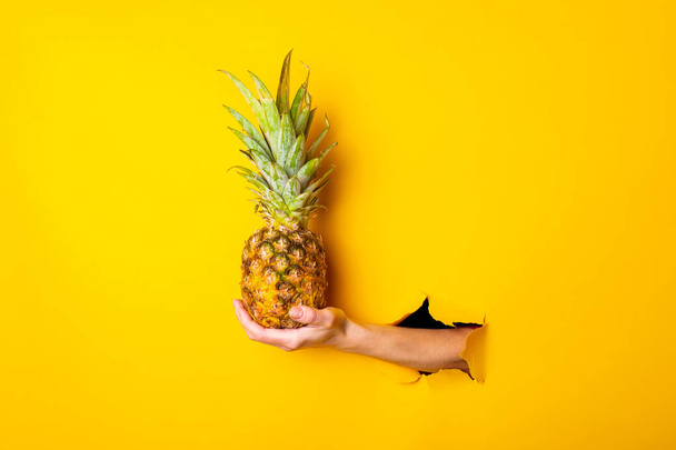 naisen käsi pitää koko ananas on revitty keltainen tausta. - Valokuva, kuva