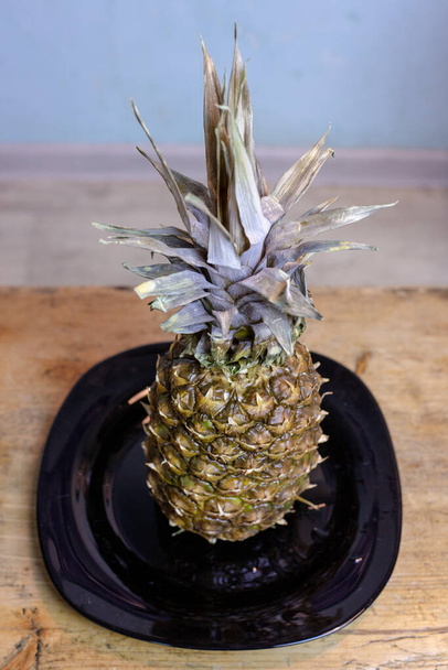 Pineapple on the kitchen table in a plate - Фото, зображення