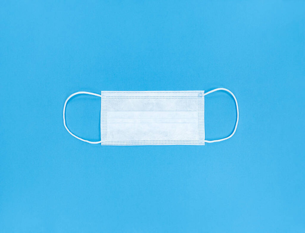 Medical disposable face mask on a blue background. - Fotoğraf, Görsel