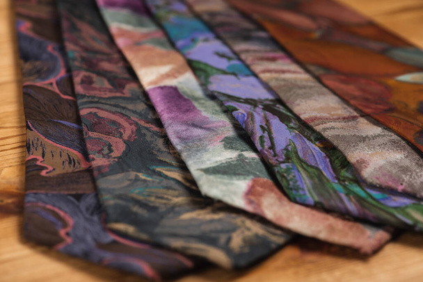 close-up view, many multi-colored folded, twisted ties, sloping horizon. Textured background of classic fabrics - Photo, Image