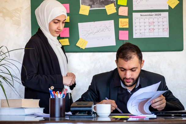 Мусульманская женщина просит поддержки и проверяет результаты своей работы у менеджера для ее производительности - Фото, изображение