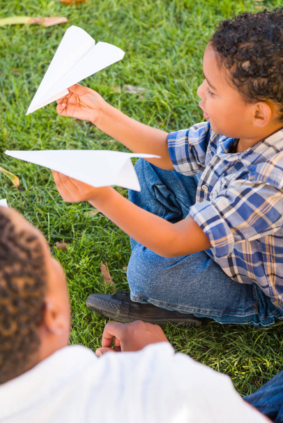 Heureux père afro-américain et fils métis jouant avec des avions en papier dans le parc. - Photo, image