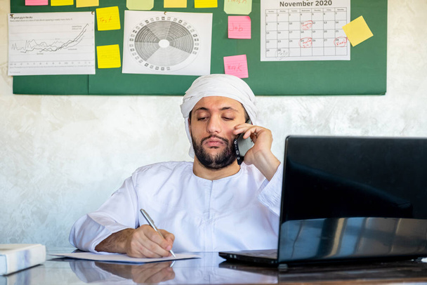 człowiek arabski korzystający z telefonu komórkowego podczas pracy w celach komunikacyjnych - Zdjęcie, obraz